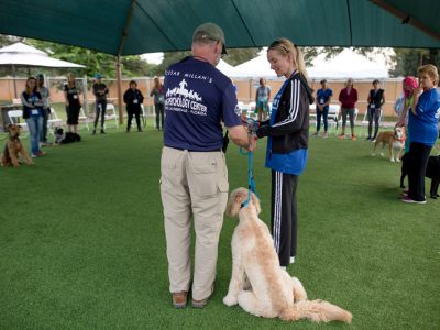 A trainer helping a pet owner to see the proper way to hold the leash